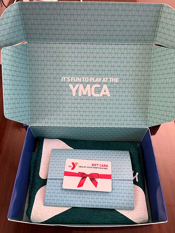 Gift card kit showing open box, YMCA logo towel, info sheets and gift card
