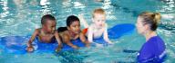 Three young swimmers on a pool float under the watchful eye of a swim instructor during All Kids Swim at the Albemarle Family YMCA