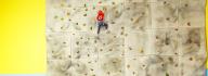 A child in safety harness climbing the rock wall at the Albemarle Family YMCA