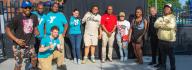 A group of members and staff stand in front of the celebration photo backdrop at the YMCA on Granby's 10th year anniversary