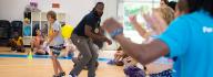 YMCA at Jt's Camp Grom counslor and camper play a game with a rubber ball between their backs while other campers watch