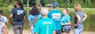 YMCA staff and donors engage in conversation while near the lake at YMCA at JT's Camp Grom