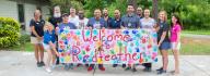 YMCA staff and donors hold the Welcome to Camp Red Feather sign