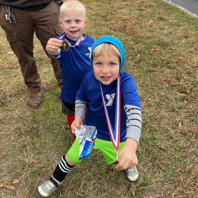 Tommy Mras and Mack O'Connor holding up their soccer medals at the Greenbrier Family YMCA