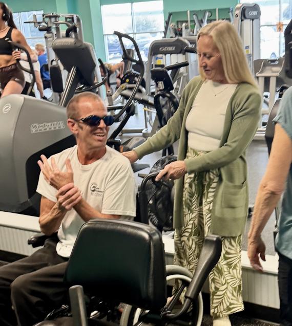 Man with sunglasses in a wheelchair with friends in the YMCA fitness center