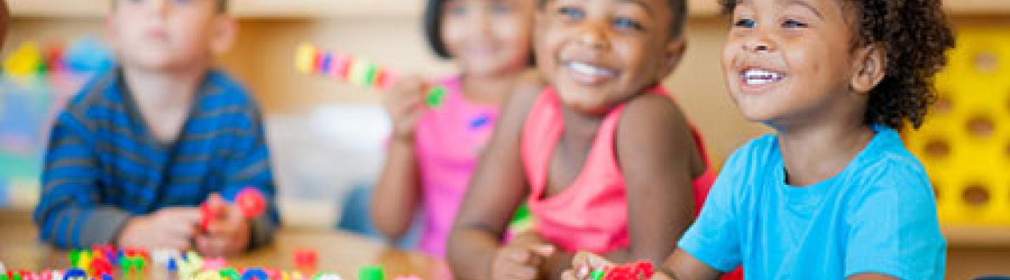 Kinder campers at table laughing and playing with blocks