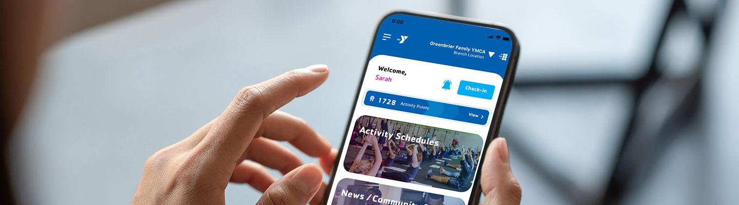 Hands hold phone, with YMCA Universal app Home Screen displaying