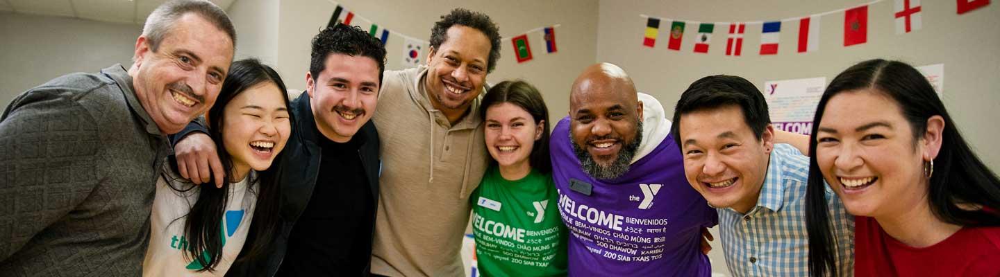 A group of YMCA staff and members with arms around each other smile happily at the camera.