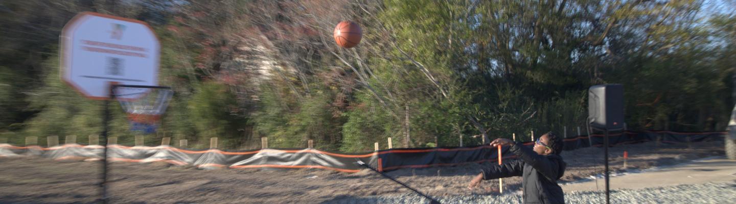 Youth shoots basketing into a hoop during NHC YMCA Groundbreaking