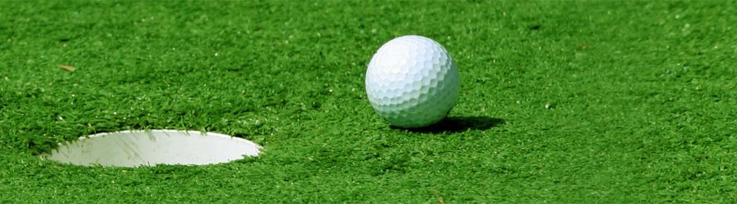 Golf ball on a putting green next to the hole