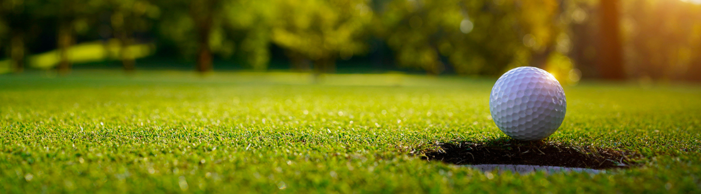 Golf ball on green grass in the evening golf course with sunshine background.