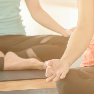 Group of people in a yoga class, with hands on knees and palms up in meditation