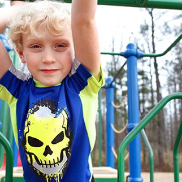 Kid in blue shirt with yellow skull on an outdoor playground