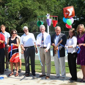 ribbon ceremony with a large group of people outside by the pool