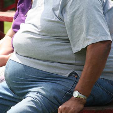 Heavy set person sitting on a bench outside