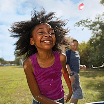 African American girl playing outside in the grass with other kids