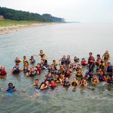 a large group of children at camp swimming in the ocean