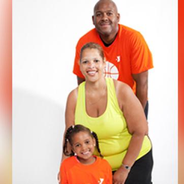 Father, mother and daughter standing in a line wearing orange and yellow shirts.