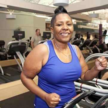 Woman in a blue tank top working out on a treadmill
