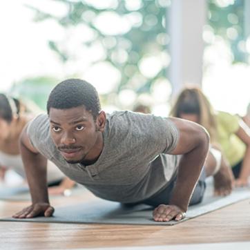 Man doing push ups on a mat in a fitness class