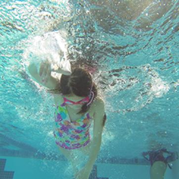 girl swimming under the water in a pool