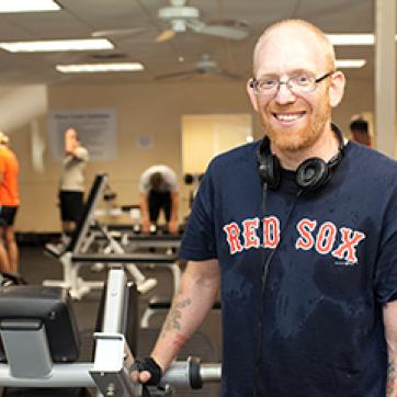 Man in Red Sox jersey working out at the YMCA