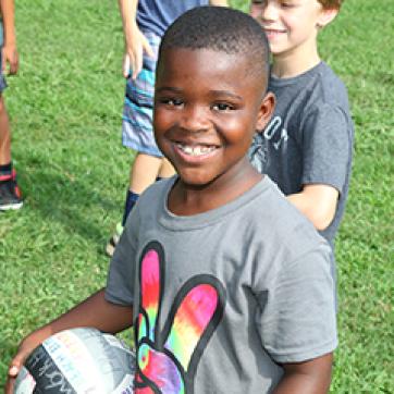 Child holding a soccer ball on the outdoor field