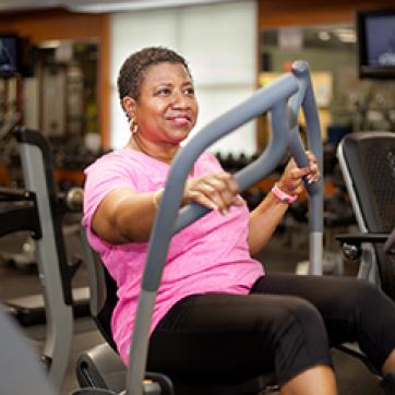 Woman in pink shirt working out in the YMCA gym