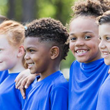Kids wearing blue shirts outside at camp
