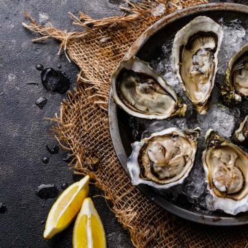 Six roasted oysters on ice, with lemons and oyster knife