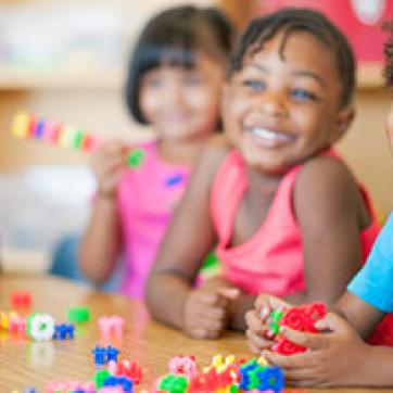 Kinder campers at table laughing and playing with blocks