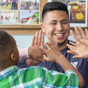 YMCA staff member high-fiving kids in YMCA child care