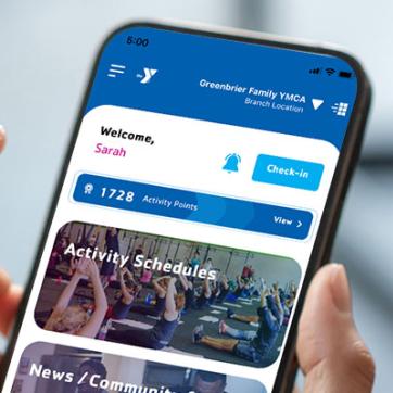 Hands hold phone, with YMCA Universal app Home Screen displaying