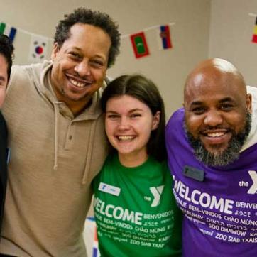 A group of YMCA staff and members with arms around each other smile happily at the camera.