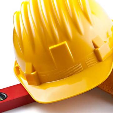 construction tools laying on a white table, including level, hard hat, and leather tool pouch with hammer, wrenches, and glue