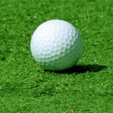 Golf ball on a putting green next to the hole