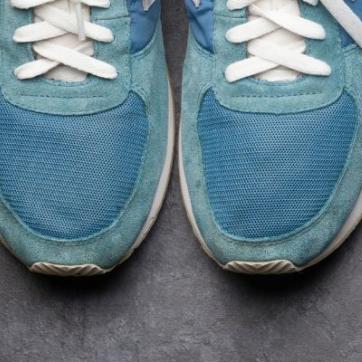 Fitness equipment on a dark floor: Sneakers, towel, water bottle, hand weights