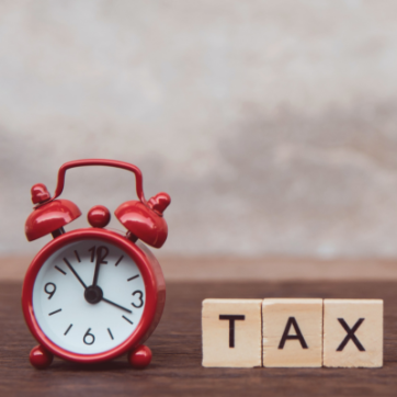 a red alarm clock next to scrabble letters that says tax