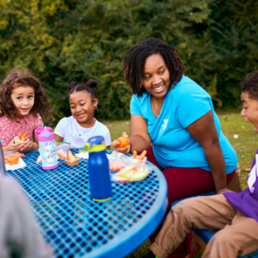 kids sitting a picnic table having lunch at summer camp