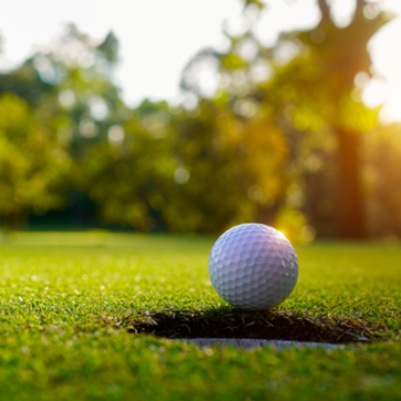 Golf ball on green grass in the evening golf course with sunshine background.