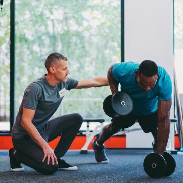 personal trainer with client lifting weights and coaching