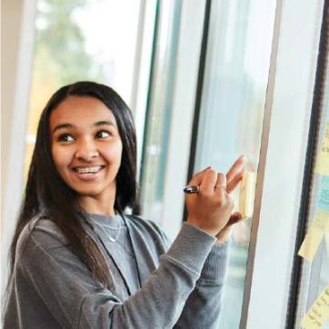 Teen girl smiling writing on post-it notes