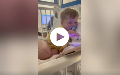 Child in hospital bed with play icon overlaid