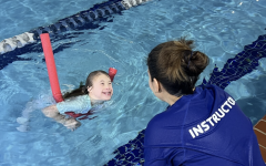 Girl in pool with pool noodle and YMCA swimming instructor