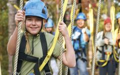 kid in a ropes climbing course in camp