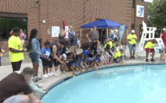 People at the edge of the pool placing rubber duckies in the pool