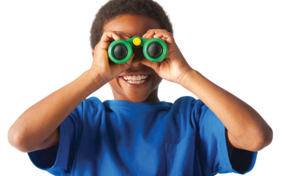 African-American boy smiling and looking at you through binoculars