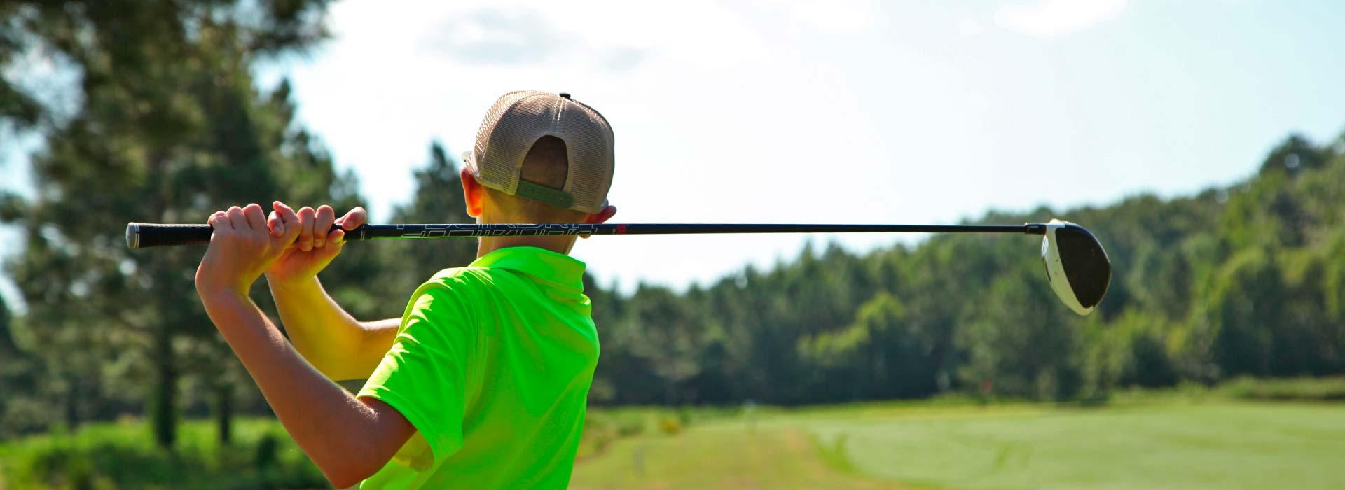 Child hitting golf ball with driver