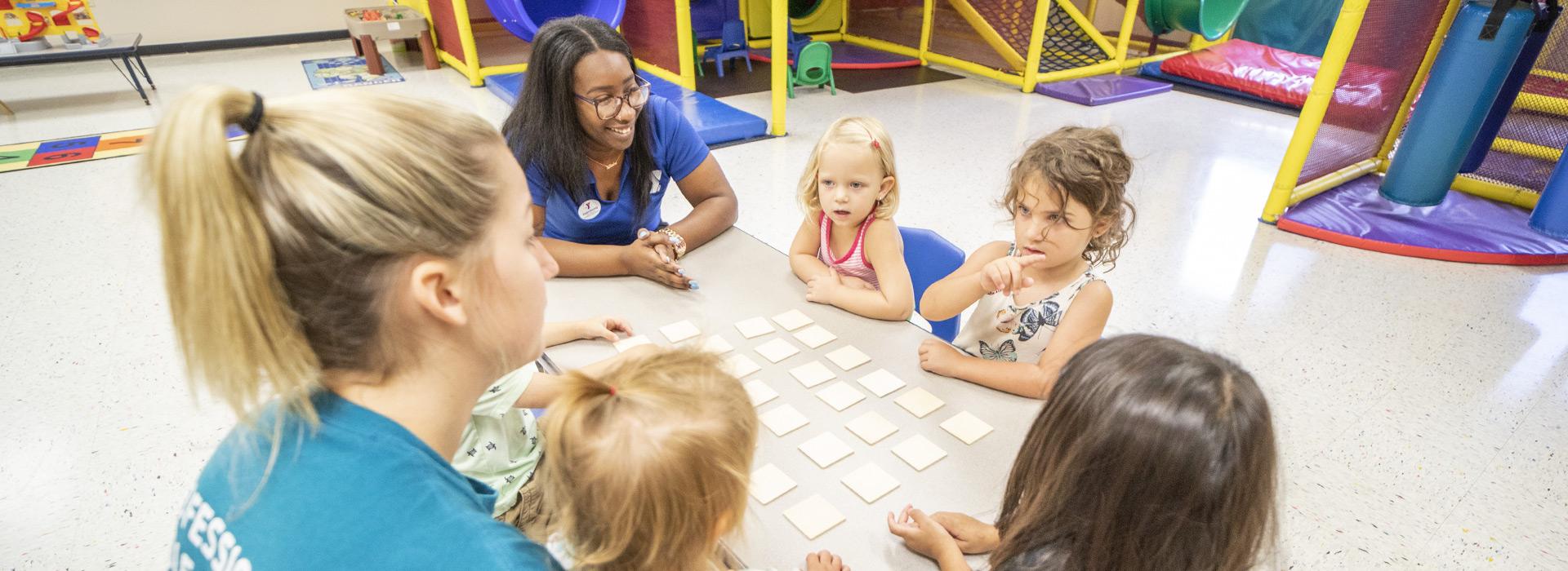 YMCA staff leading a game of memory with preschool aged girls in Stay & Play at the Albemarle Family YMCA