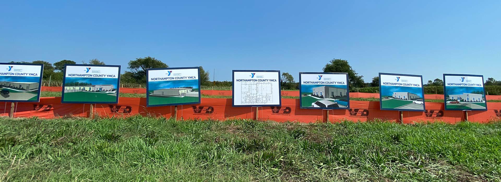 Artist rendering and floor plan signs in the grass at the groundbreaking ceremony for the Northampton County YMCA.